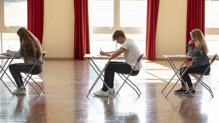 Group Of Teenage Students Sitting Examination In School Hall