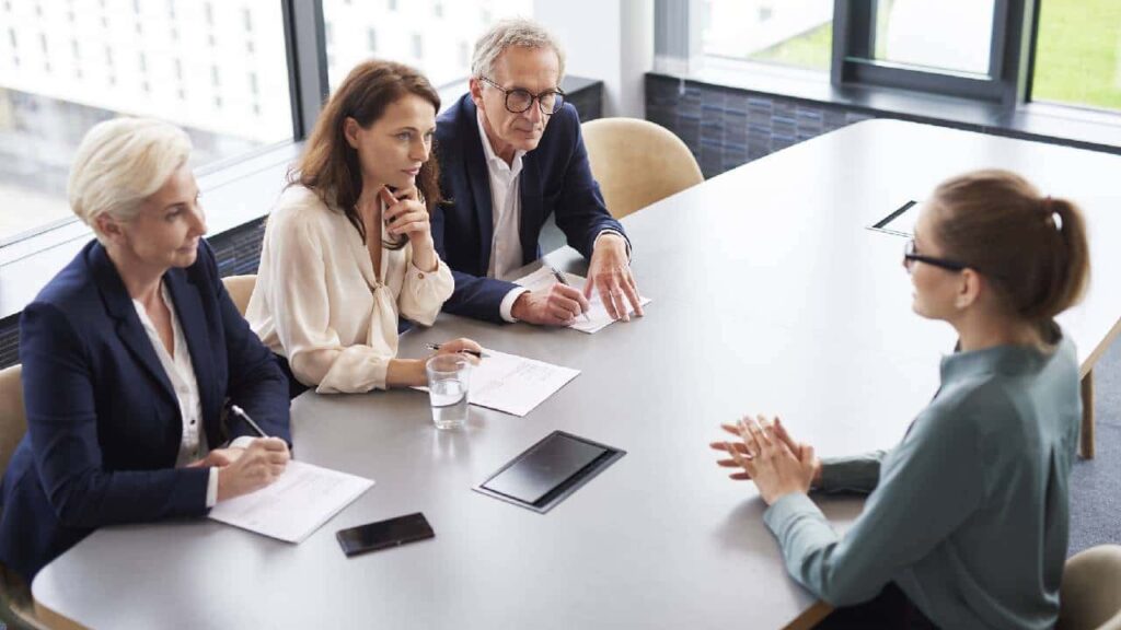 Woman during job interview and three elegant members of management.