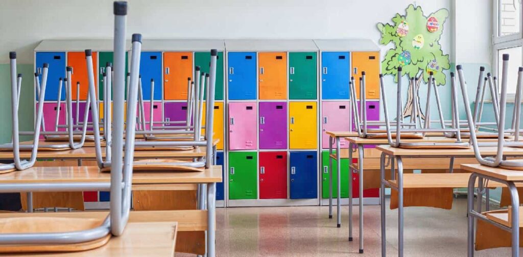 Classroom with colorful lockers and raised chairs on the tables as school is closed for the summer holidays.