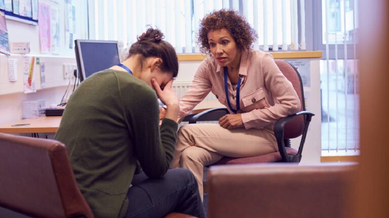 Female College Student Meeting With Campus Counselor Discussing Mental Health