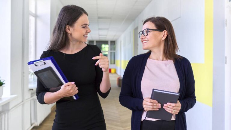 Two colleagues of businesswoman walking and talking on corridor