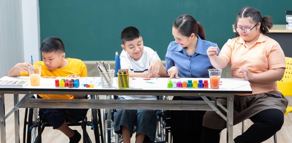 Asian group of disabled kids or autism child learning and painting at paper with their send teaching assistant helping in classroom