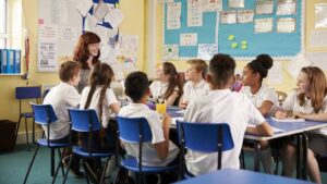 School teacher and kids work on class project,