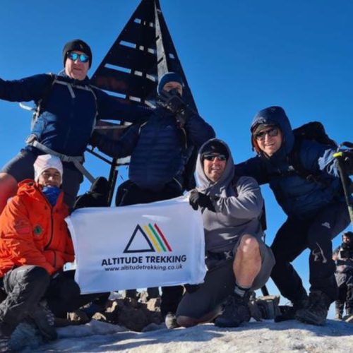 Hannah and team posing with the flag after climing Mount Toubkal